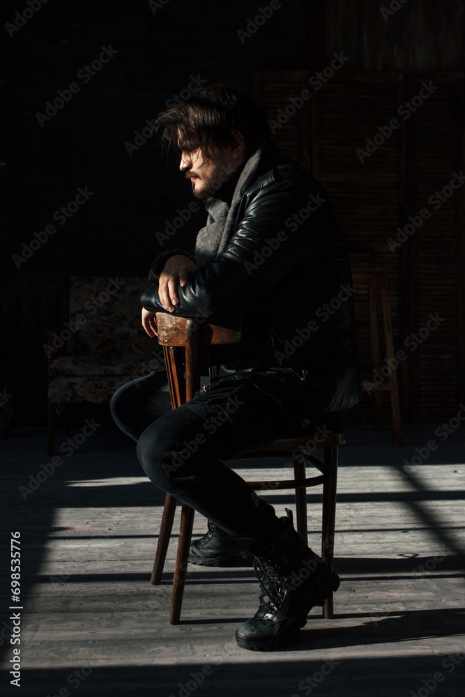 handsome man in black clothes sitting on a chair - obrazy, fototapety, plakaty 