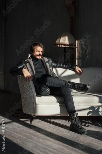handsome man in black clothes sitting on a chair