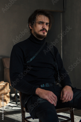 handsome man in black clothes sitting on a chair