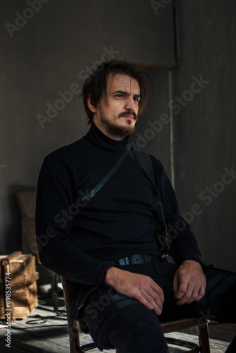 handsome man in black clothes sitting on a chair