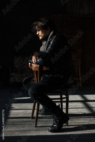 handsome man in black clothes sitting on a chair photo