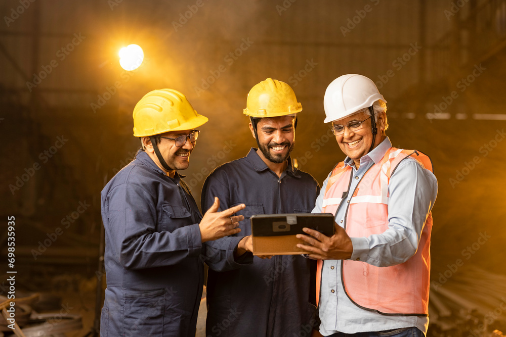 Mechanic with engineer using digital tablet and discussing at factory Mechanic with engineer using digital tablet and discussing at factory