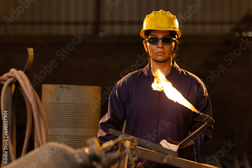 Female industrial worker working with blow torch in factory photo
