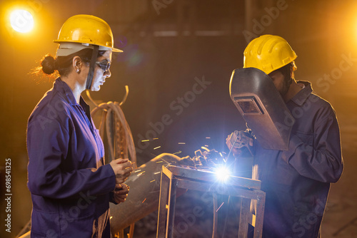 Industrial worker welding metal part at factory