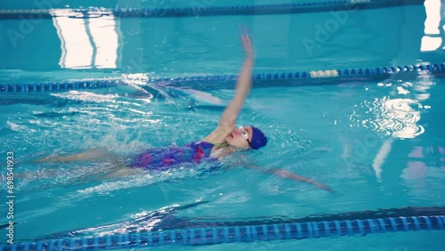 A young woman swimmer in the pool swims using the backstroke technique, Back Crawl. Beautiful attractive girl enjoys swimming. photo