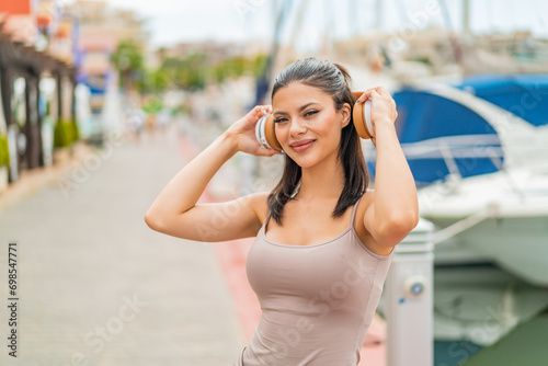 Young pretty woman at outdoors listening music