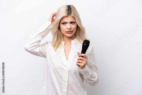 Young singer woman picking up a microphone isolated on white background having doubts