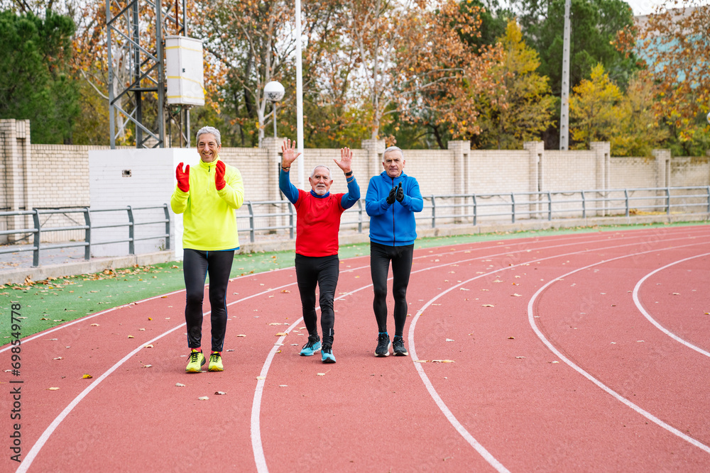 Three joyful seniors engage in fitness on a track, exuding vitality and happiness. Active lifestyle concept for elderly people.
