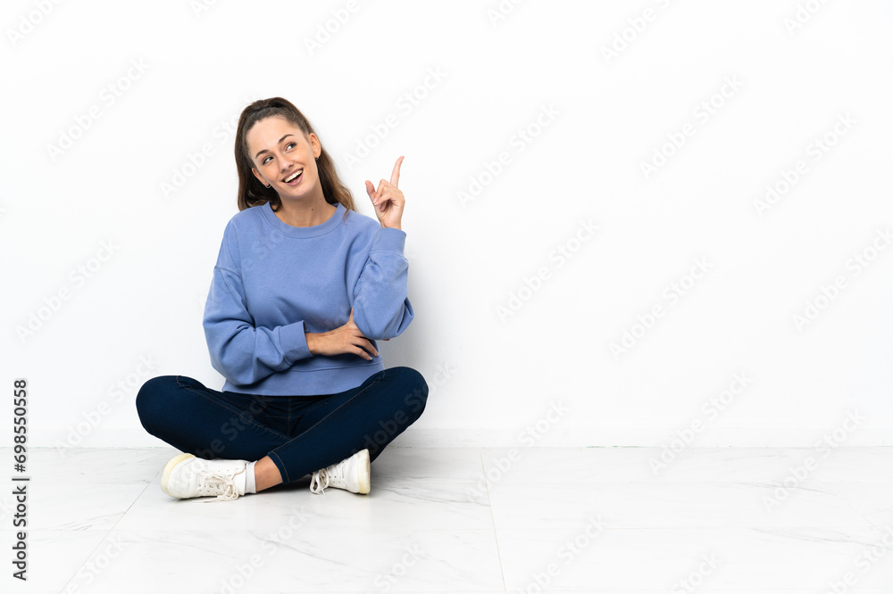 Young woman sitting on the floor pointing up a great idea Young woman sitting on the floor pointing up a great idea