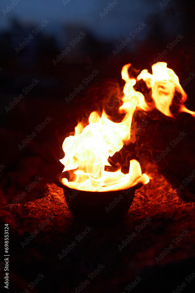 Vertical closeup of red flaming fire in bowl set for spiritual ritual outdoors Vertical closeup of red flaming fire in bowl set for spiritual ritual outdoors