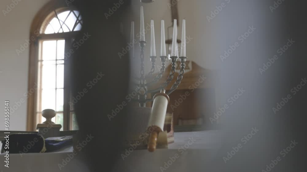 A slow motion video in a synagogue revealing religious scrolls and a candlestick with multiple candles
