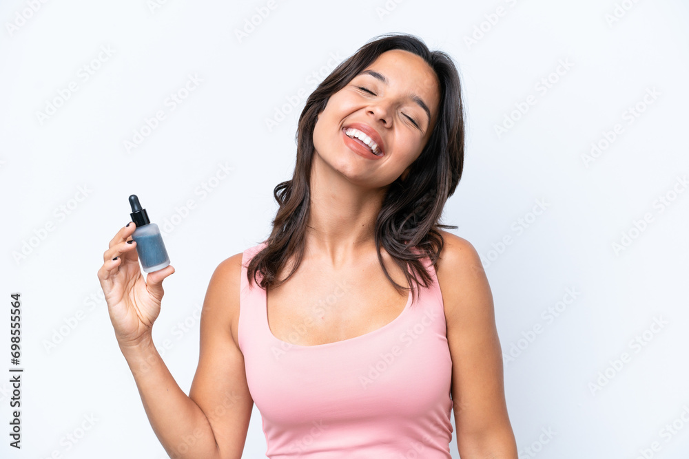 Young hispanic woman holding serum isolated on white background laughing Young hispanic woman holding serum isolated on white background laughing