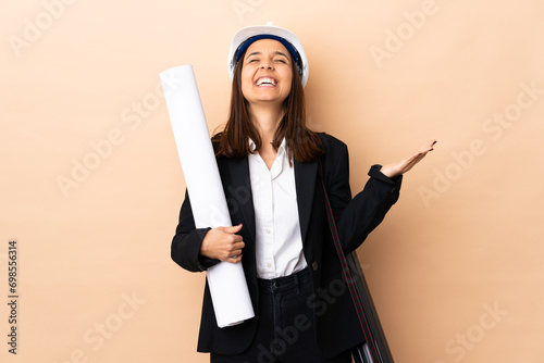 Young architect woman holding blueprints over isolated background smiling a lot