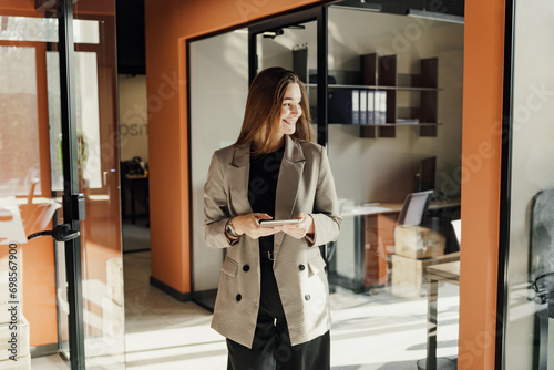 A female marketer in the office uses a phone and a business app to communicate with a client. An employee of the company in a jacket.