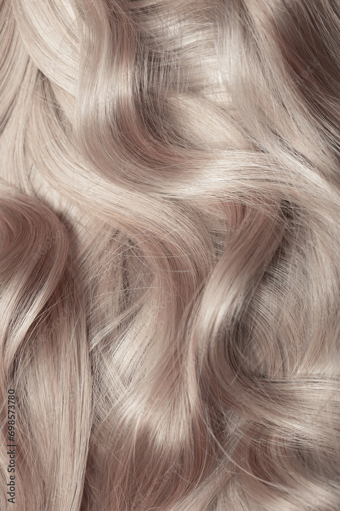 Naklejka premium Blond hair close-up as a background. Women's long light brown hair. Beautifully styled wavy shiny curls. Hair coloring. Hairdressing procedures, extension.