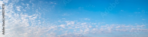 wide sky panorama with fleecy clouds in the lower half and blue space above