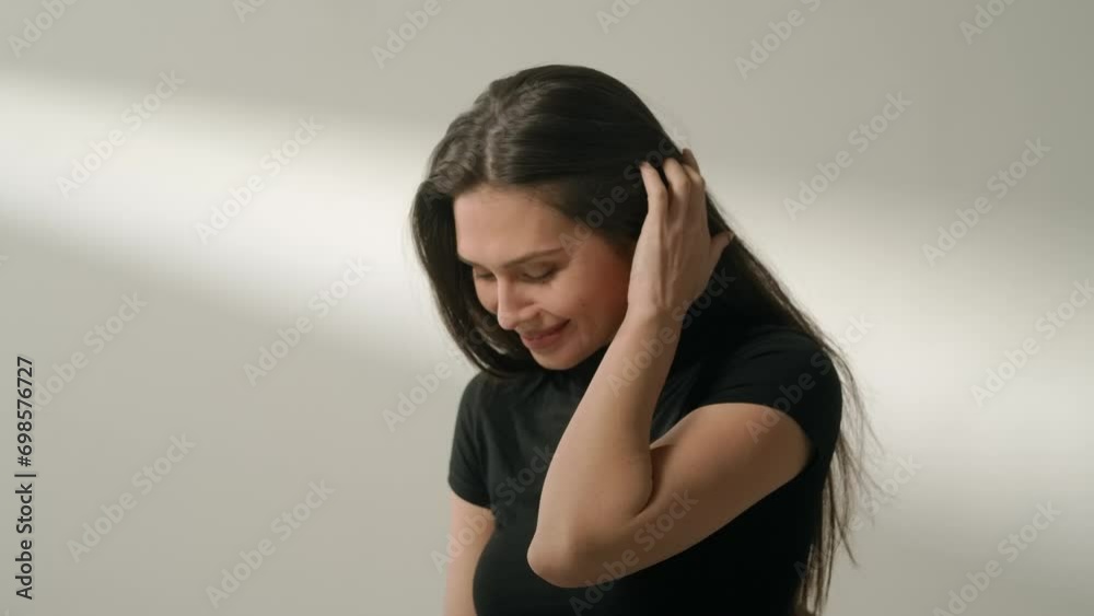 Portrait of attractive female model in positive mood. Brunette woman in casual clothing sitting in the studio fixing hair and smiling. Portrait of attractive female model in positive mood. Brunette woman in casual clothing sitting in the studio fixing hair and smiling.