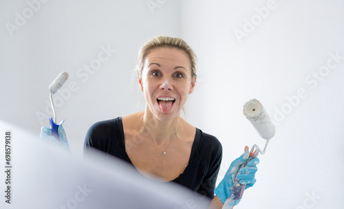 Close up of a blonde woman is having fun, sticking out her tongue while painting