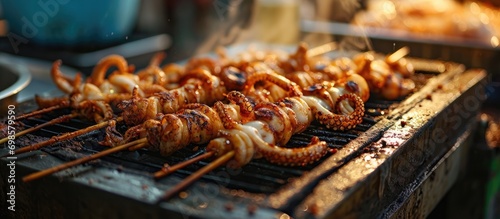 Thai street food: skewered squid cooked on stove. photo