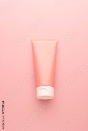 Blank pink squeeze bottle plastic tube on pink background. Packaging of cream, lotion, gel, facial foam or skincare. Cosmetic beauty product branding mock-up. Vertical. photo