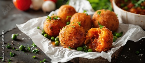 Sicilian arancini with meat stew and peas, street food in Palermo, on white paper in Italian. photo