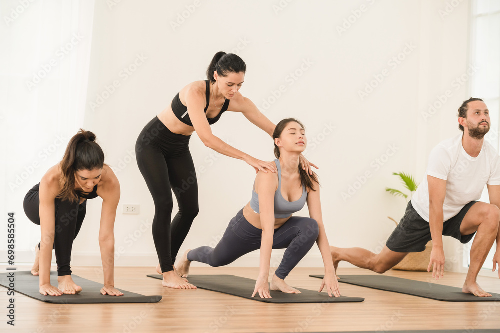 Obraz premium Happy yoga instructor enjoying while teaching a group class to young people in studio