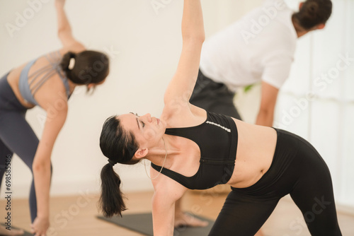 Happy yoga instructor enjoying while teaching a group class to young people in studio