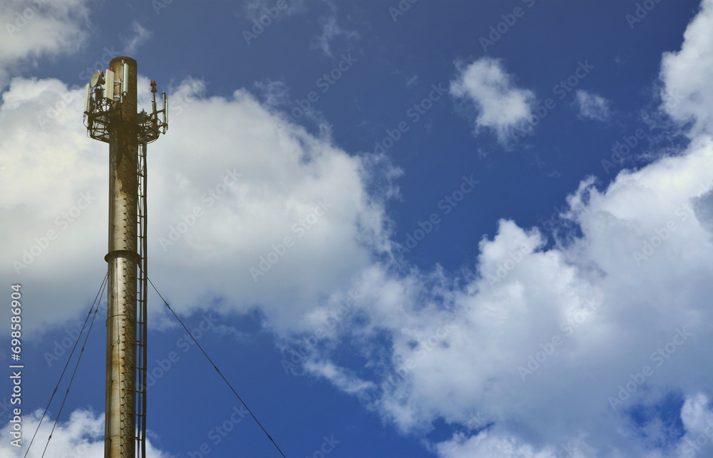 High metal chimney of industrial plant with ladder in the form of metal braces against the background of a cloudy blue sky High metal chimney of industrial plant with ladder in the form of metal braces against the background of a cloudy blue sky
