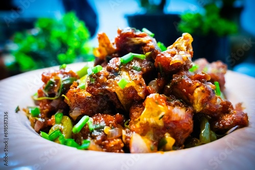 Gobi Manchurian Homemade, Indo Chinese fried Cauliflower florets, Gobi Manchurian is Indian Chinese cuisine dish with cauliflower, tomatoes, onion, soy sauce in white plate selective focus. photo