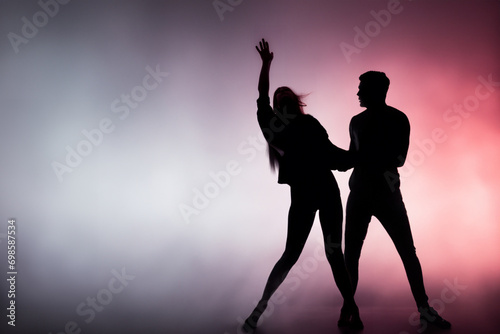 couple silhouette. a man and a girl dancing hip-hop, multi-colored smoke on the background. dance concept
