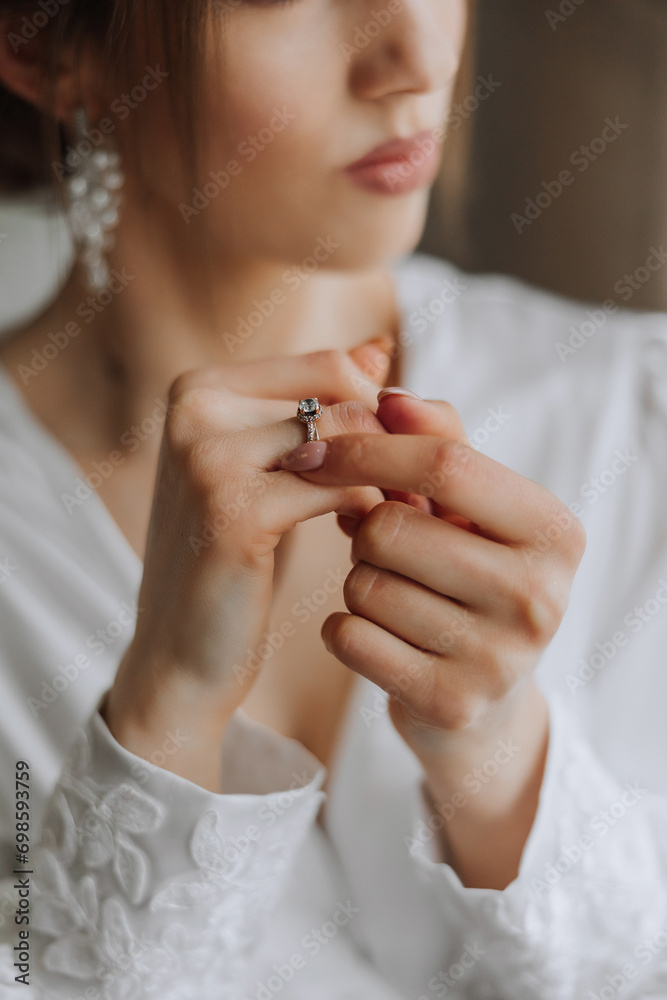 Fototapeta premium Close-up of an elegant diamond ring on a woman's finger with a modern manicure, sunlight. Love and wedding concept. Soft and selective focus.