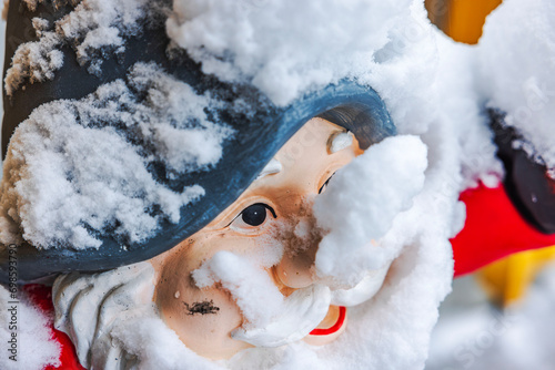 Close-up view of snow-covered gnome face for outdoor decoration at entrance of house on frosty winter day. Sweden.