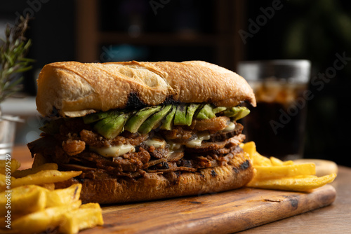 Traditional Peruvian sandwich of roast beef in its juice with avocado and white onion, served on ciabbata bread with a portion of French fries. photo