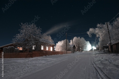 winter evening in the village house next to the road smoke from the chimney snow