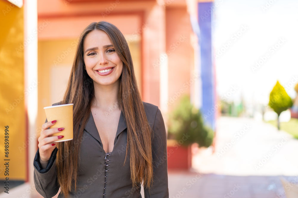 Young woman holding a take away coffee at outdoors smiling a lot Young woman holding a take away coffee at outdoors smiling a lot