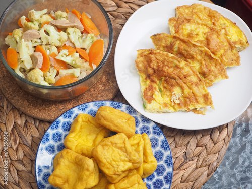 Reguler family food, delicious food, Vegetable sauté cauliflower, carrots,meatballs with fried Yellow tofu and Telur dadar (Indonesian omelet eggs) photo