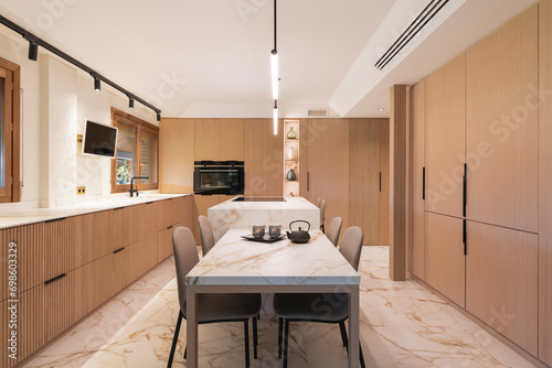 Hermosa y amplia cocina hecha de madera con acabados de calidad y con isla central y suelos de mármol.