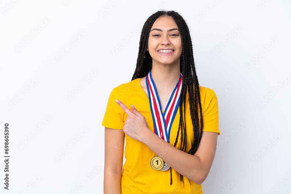 Teenager girl with braids and medals over isolated pink background pointing to the side to present a product Teenager girl with braids and medals over isolated pink background pointing to the side to present a product