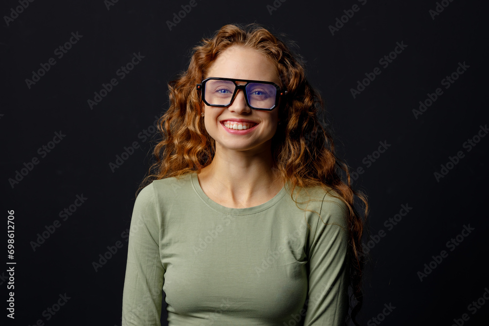 Happy smiling curly young woman wearing glasses looking at camera with joyful smile