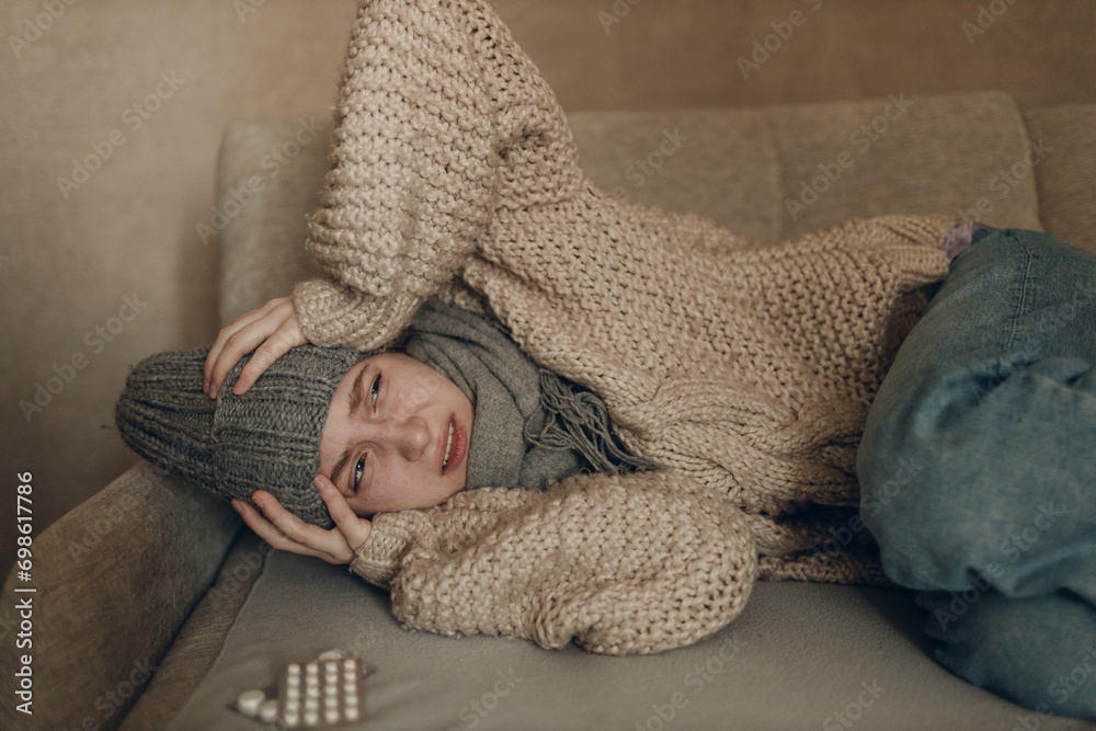 Young woman wearing scarf has flu ill sick disease cold at home indoor on sofa Young woman wearing scarf has flu ill sick disease cold at home indoor on sofa