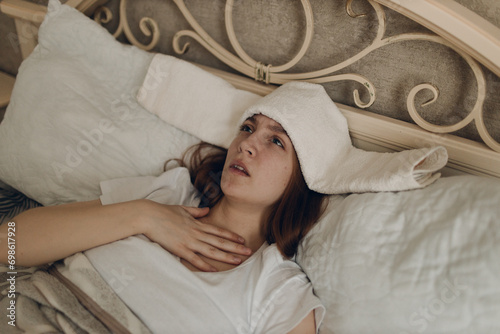 Foto Young woman with headache flu ill sick disease cold at home indoor lying on bed