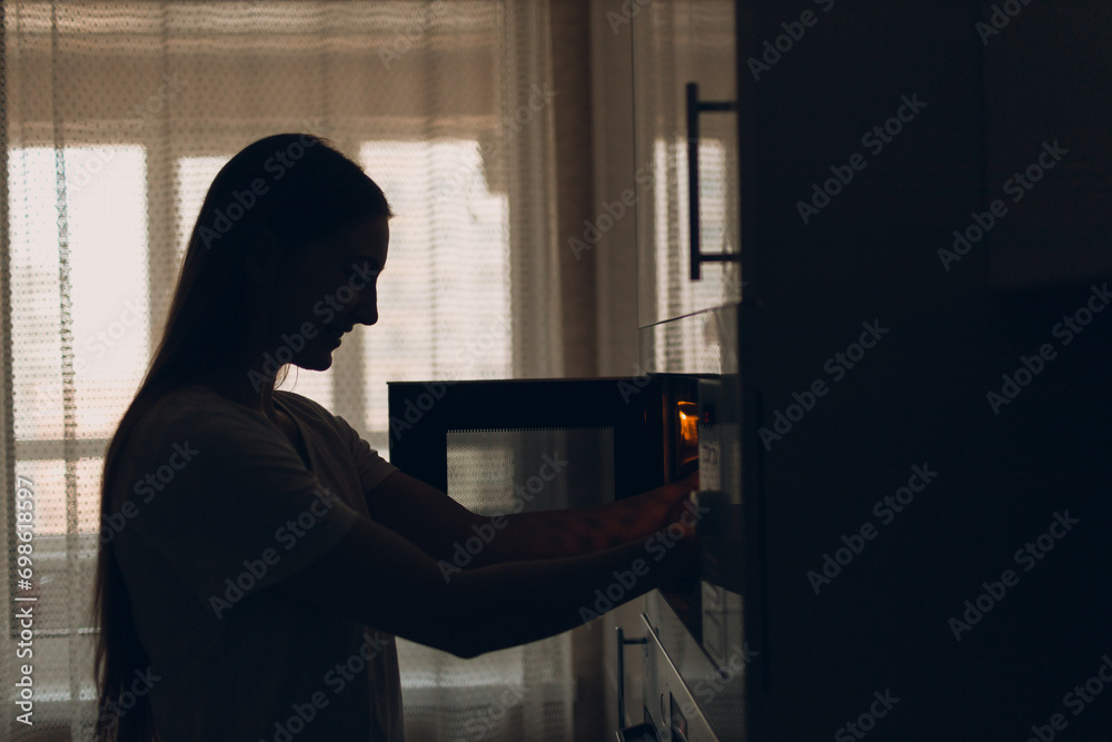 A housewife woman cooks food and looks into the oven in the kitchen.