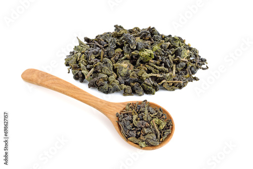 Dry tea in wooden spoon with heap dry tea leaves, isolated on white background