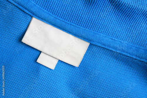 Blank white laundry care clothes label on blue shirt fabric texture background