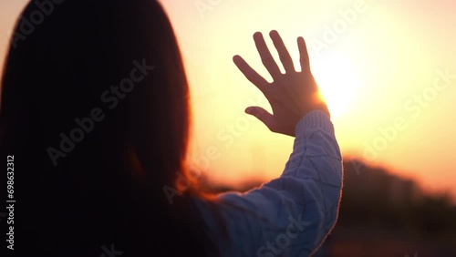Silhouette of a happy dreaming girl pulls her hand to the sunset golden hour, Hand of female touch the first sunrise on New Year. photo