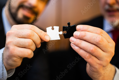 Close-up of two businessmen collaborating by connecting jigsaw p