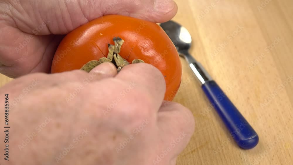 Person eats the flesh of whole persimmon with a spoon
