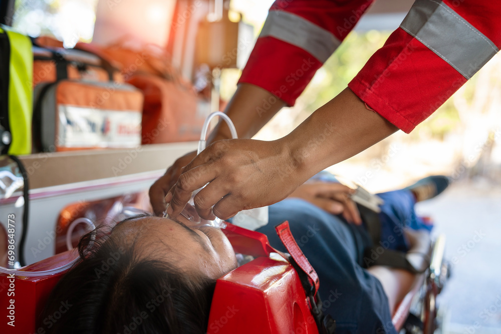 Emergency medical service male nurse rescuer helping a male patient lie on a board performing chest compressions and connecting to a ventilator in an ambulance - obrazy, fototapety, plakaty 
