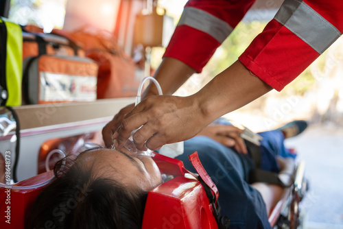 Emergency medical service male nurse rescuer helping a male patient lie on a board performing chest compressions and connecting to a ventilator in an ambulance