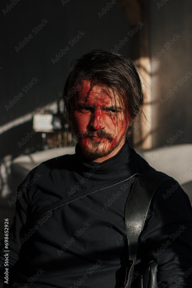 Obraz premium a tired man with a broken face covered in blood sits by the window. guy with makeup, cosplay